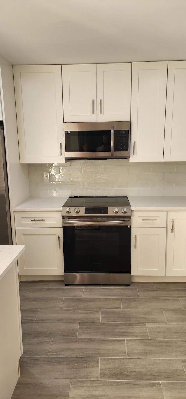 kitchen featuring stainless steel appliances, white cabinetry, and tasteful backsplash