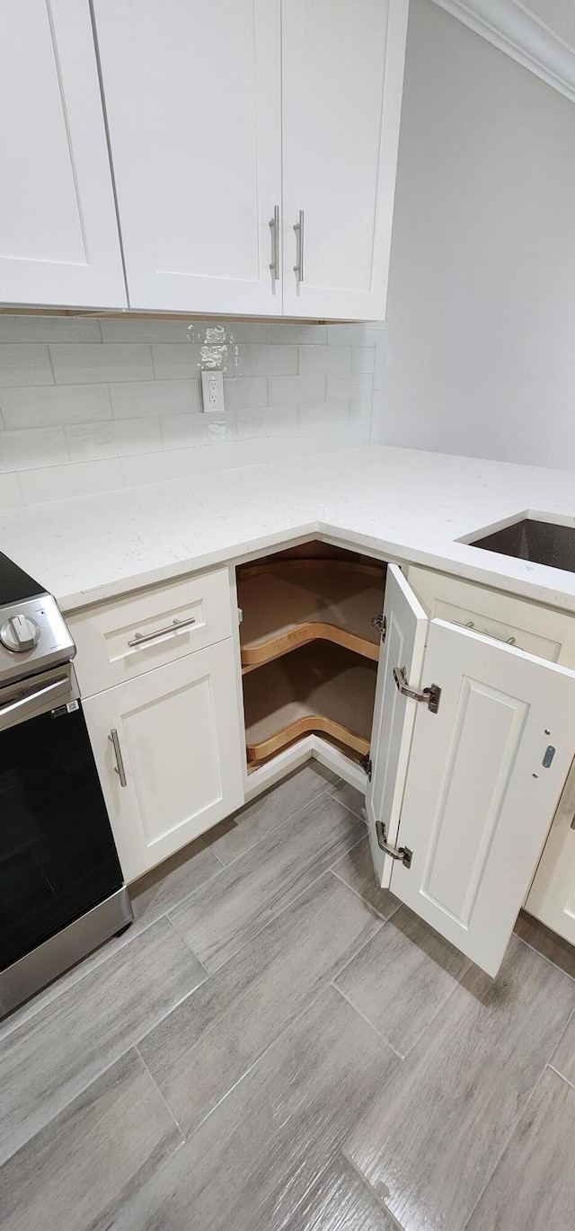 kitchen featuring white cabinets, decorative backsplash, light stone countertops, stainless steel electric range oven, and light hardwood / wood-style floors