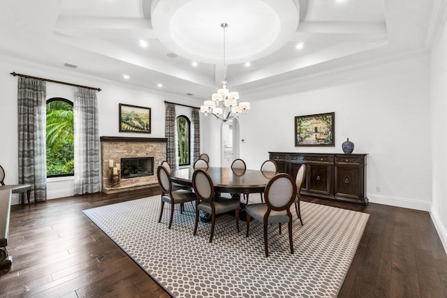 dining area with a notable chandelier, dark hardwood / wood-style flooring, a fireplace, and a tray ceiling