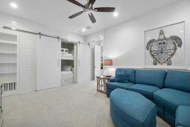 living room with a barn door, light colored carpet, and ceiling fan