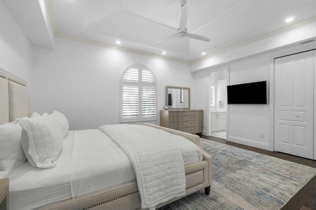 bedroom with ensuite bath, ornamental molding, a raised ceiling, ceiling fan, and dark hardwood / wood-style floors