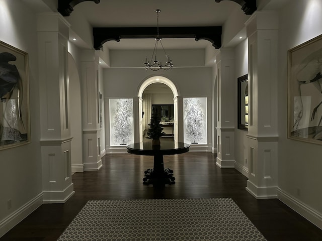 interior space featuring beam ceiling, dark hardwood / wood-style flooring, decorative columns, and an inviting chandelier