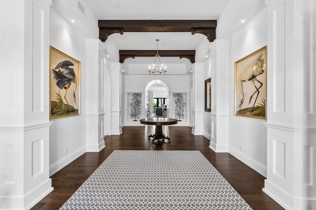 corridor with beamed ceiling, dark wood-type flooring, and decorative columns