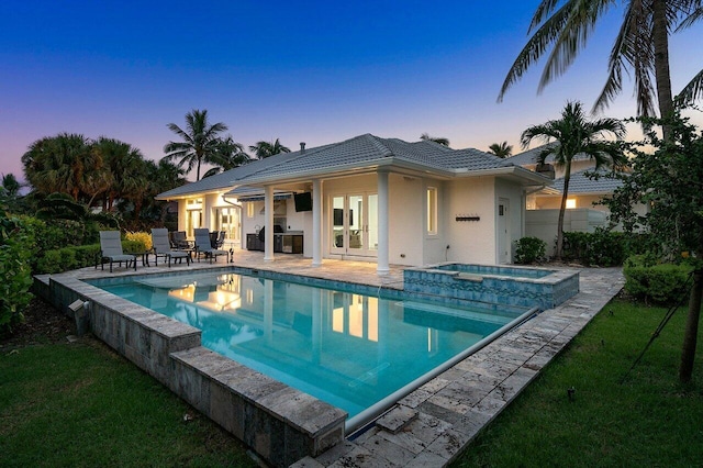 pool at dusk featuring an in ground hot tub, french doors, and a patio