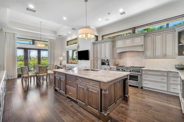 kitchen featuring a raised ceiling, sink, double oven range, and decorative light fixtures