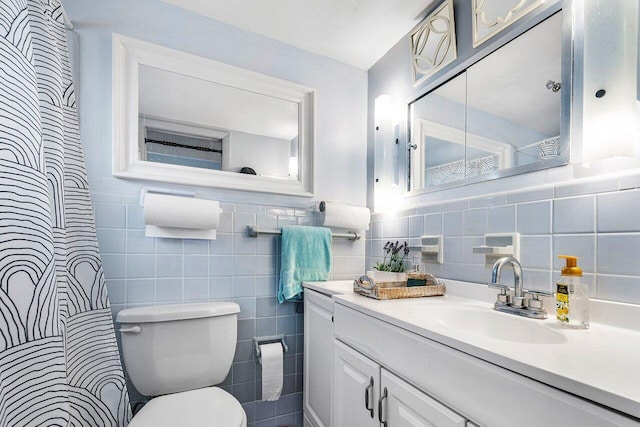 bathroom with vanity, toilet, and tile walls