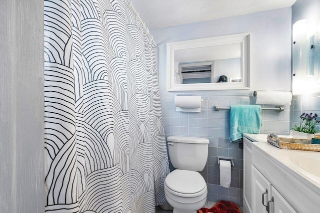 bathroom with vanity, toilet, tile walls, and walk in shower