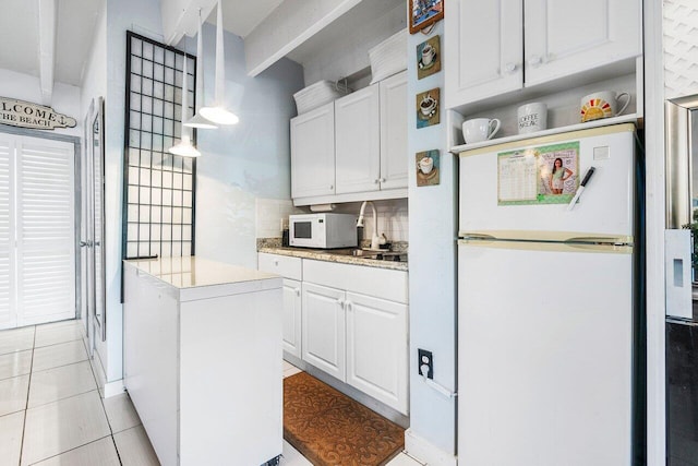 kitchen featuring decorative backsplash, white appliances, pendant lighting, light tile patterned floors, and white cabinets