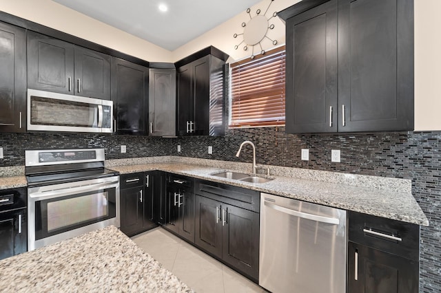 kitchen with backsplash, light stone countertops, sink, and stainless steel appliances