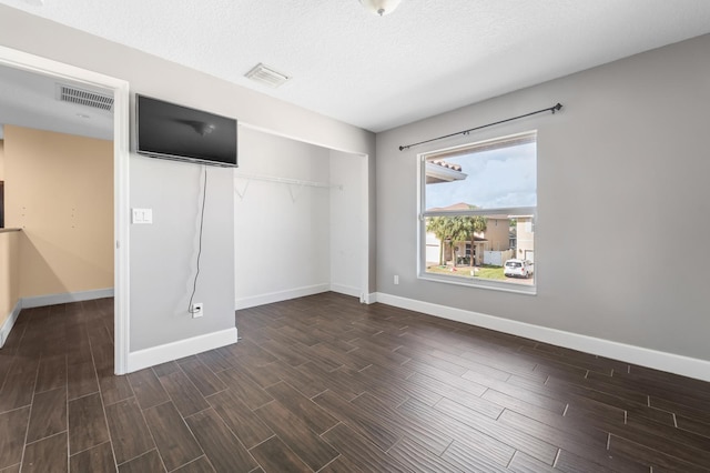 unfurnished bedroom with dark hardwood / wood-style floors, a textured ceiling, and a closet