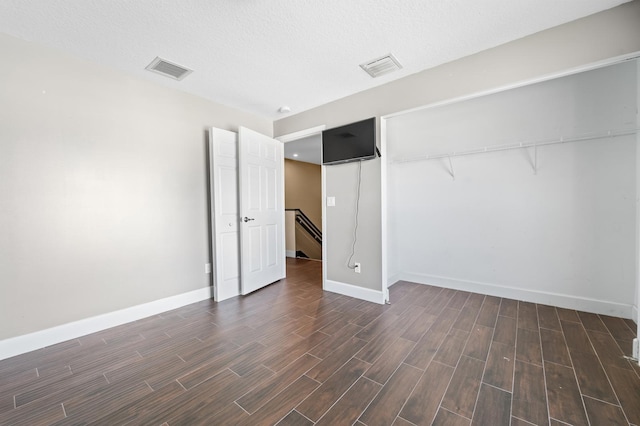 unfurnished room with a textured ceiling and dark hardwood / wood-style flooring