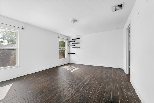 spare room featuring a textured ceiling and dark hardwood / wood-style floors