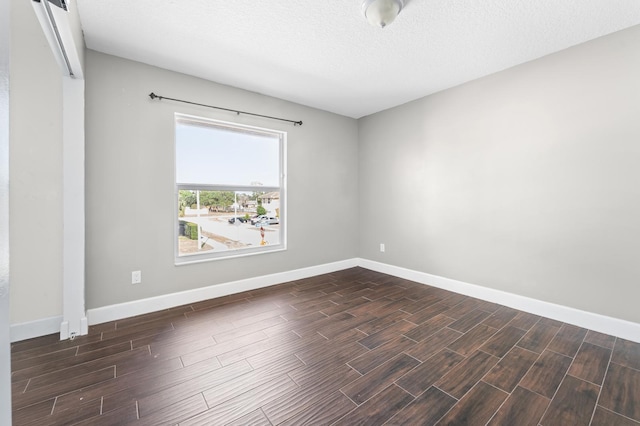 empty room featuring a textured ceiling and dark hardwood / wood-style flooring