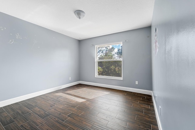 spare room with dark hardwood / wood-style flooring and a textured ceiling