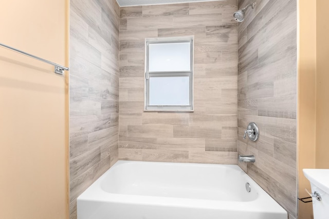 bathroom featuring toilet and tiled shower / bath