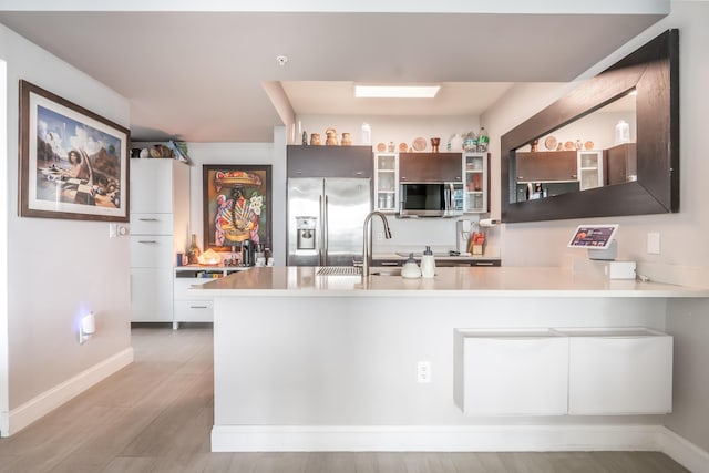 kitchen featuring kitchen peninsula, light wood-type flooring, stainless steel appliances, and sink