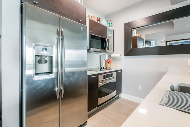 kitchen with dark brown cabinets, stainless steel appliances, and light hardwood / wood-style floors