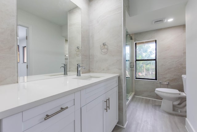 bathroom with hardwood / wood-style floors, vanity, toilet, tile walls, and walk in shower