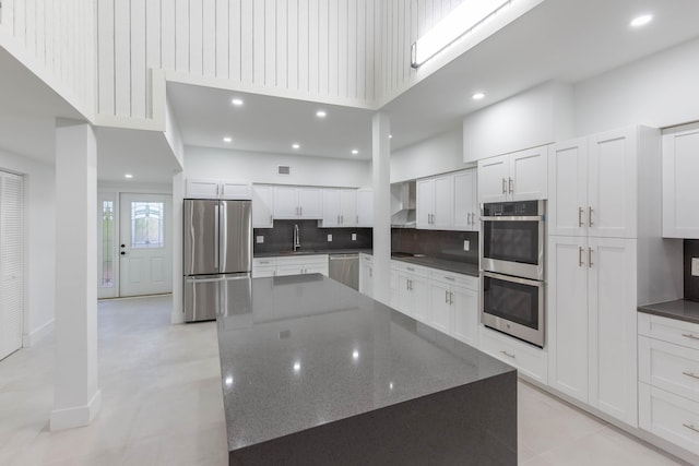 kitchen with white cabinets, a spacious island, sink, decorative backsplash, and appliances with stainless steel finishes