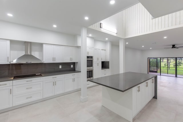 kitchen with black electric cooktop, a large island, white cabinets, and wall chimney range hood