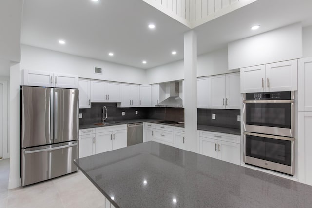 kitchen featuring white cabinetry, wall chimney range hood, and appliances with stainless steel finishes