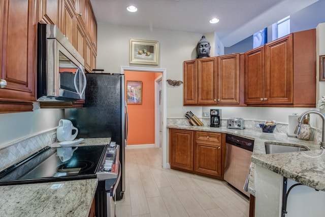 507 Resort Ln, Palm Beach Gardens, FL 33418 - kitchen featuring stainless steel appliances, a sink, light stone counters, brown cabinets, and recessed lighting