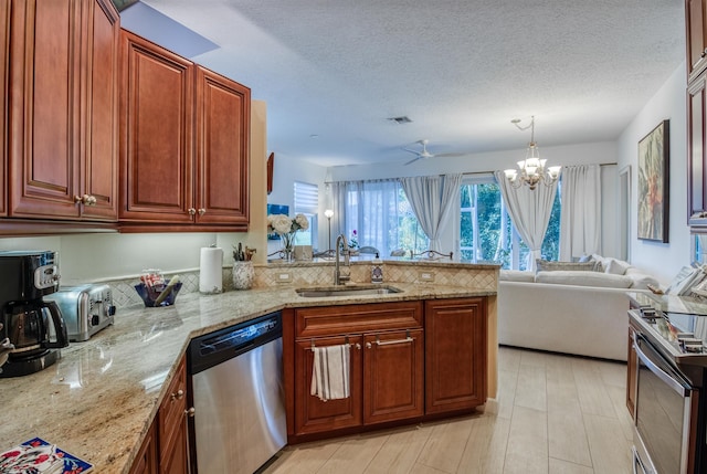 kitchen with sink, a textured ceiling, decorative light fixtures, light stone counters, and stainless steel appliances