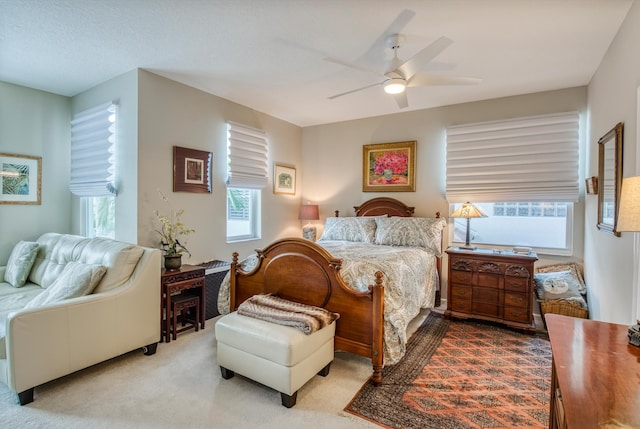 bedroom with multiple windows, ceiling fan, and light colored carpet