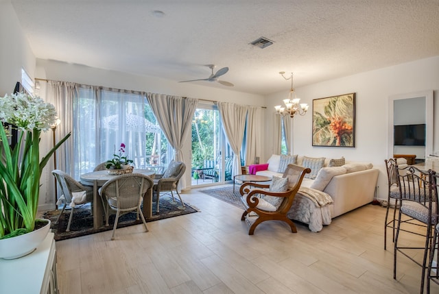 living room featuring a textured ceiling, ceiling fan with notable chandelier, and light hardwood / wood-style flooring