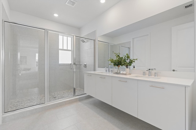 bathroom with a shower with door, vanity, and tile patterned flooring