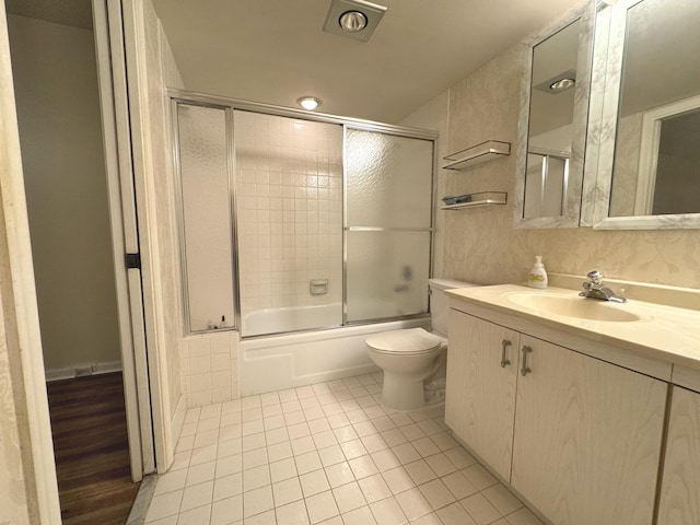 full bathroom with tile patterned flooring, vanity, bath / shower combo with glass door, and toilet