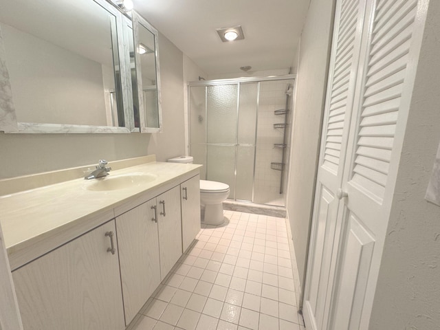 bathroom featuring tile patterned flooring, vanity, toilet, and a shower with shower door