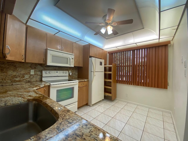 kitchen with ceiling fan, backsplash, dark stone countertops, white appliances, and light tile patterned floors