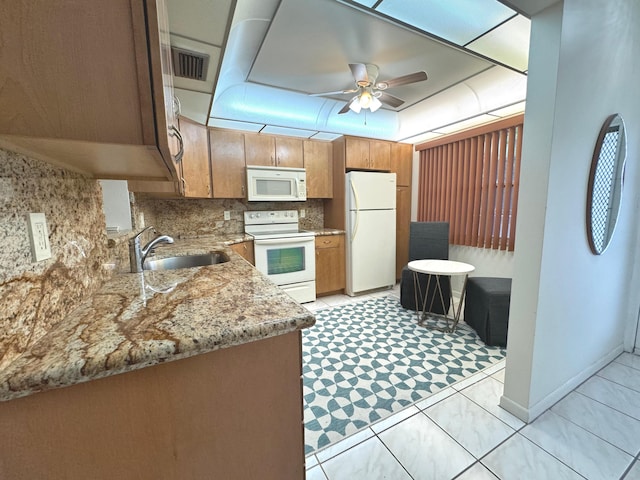 kitchen featuring ceiling fan, sink, light stone counters, white appliances, and decorative backsplash