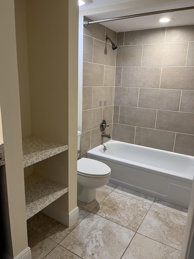 bathroom with tile patterned flooring, tiled shower / bath combo, and toilet