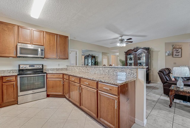 kitchen with appliances with stainless steel finishes, light tile patterned floors, ceiling fan, and kitchen peninsula