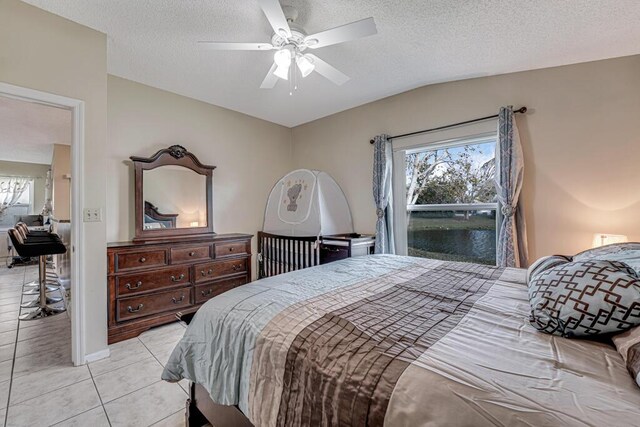 tiled bedroom with ceiling fan, vaulted ceiling, multiple windows, and a textured ceiling