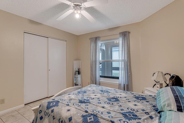 tiled bedroom with ceiling fan, a closet, and a textured ceiling