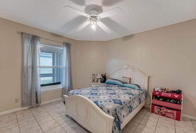 bedroom featuring ceiling fan, light tile patterned floors, and a textured ceiling