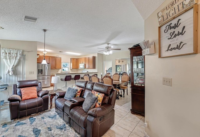 living room featuring ceiling fan, light tile patterned floors, and a textured ceiling