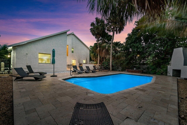 pool at dusk featuring a patio area