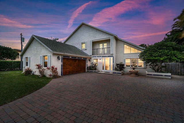 view of property featuring a lawn, a balcony, and a garage