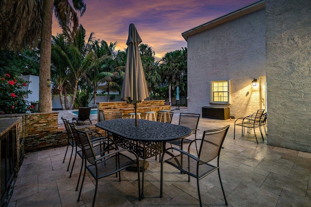 patio terrace at dusk with a fenced in pool