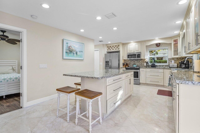 kitchen with a center island, backsplash, sink, a kitchen bar, and stainless steel appliances