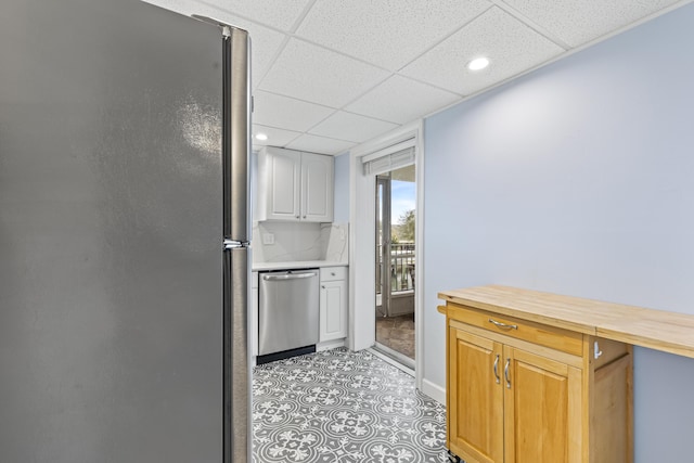 kitchen featuring appliances with stainless steel finishes, a paneled ceiling, butcher block counters, and backsplash