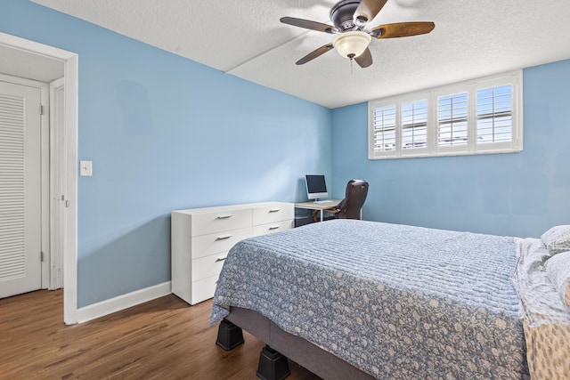 bedroom with ceiling fan, dark hardwood / wood-style floors, and a textured ceiling