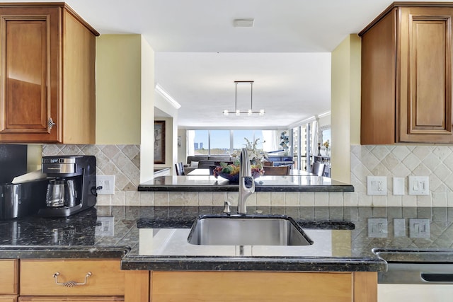 kitchen featuring backsplash, dishwasher, dark stone countertops, and sink