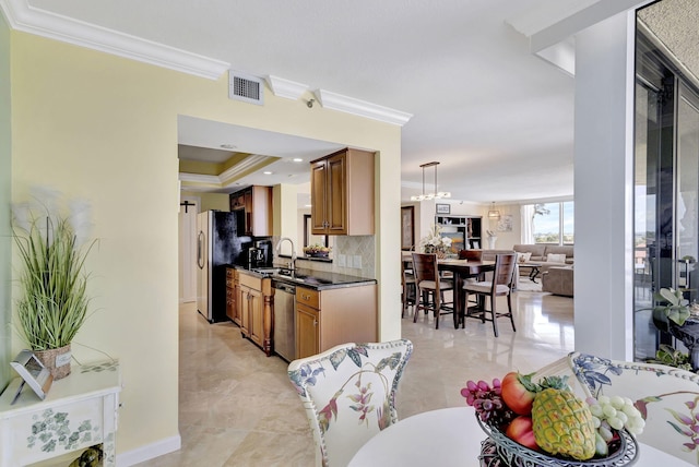 kitchen with sink, stainless steel appliances, decorative light fixtures, decorative backsplash, and ornamental molding