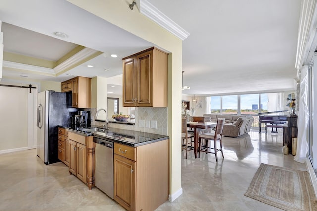 kitchen featuring dark stone counters, sink, a barn door, ornamental molding, and appliances with stainless steel finishes