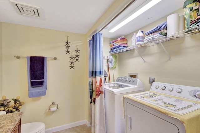 laundry area with washer and clothes dryer and light tile patterned floors